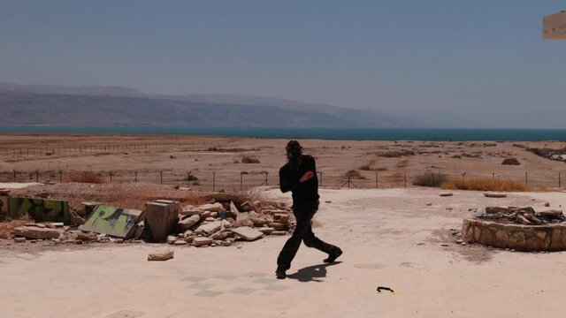 Post apocalypse workout &ndash; man practicing Capoeira footwork between ruins, with a gas mask on his face.