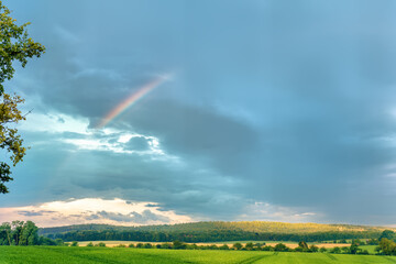 A rainbow over the green and sunny fields