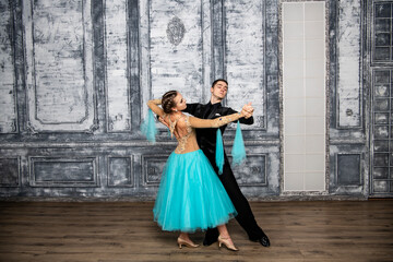 young couple in evening dance costumes dancing tango in the ballroom