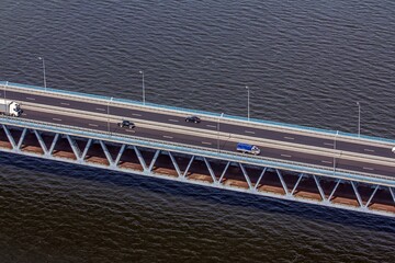 Beautiful top aerial view of Presidential bridge (opened in 2009, 5.8km length) over the river Volga and trucks driving along the road. Ulyanovsk, Russia..