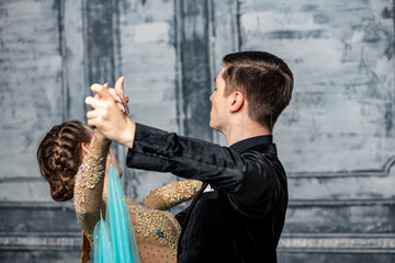 young couple in evening dance costumes dancing tango in the ballroom