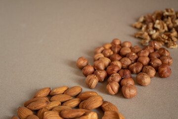 Three types of nuts lie on a horizontal surface. Walnuts, hazelnuts and almonds lie on a diagonal line. Peeled nuts for a healthy diet.