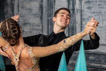 young couple in evening dance costumes dancing tango in the ballroom