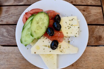 plate of cheese tomato cucumber and olives on a wooden table