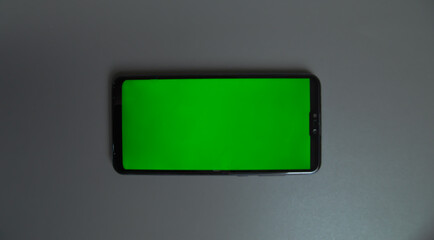 cell phone with chroma screen next to biosecurity elements and laptop keyboard on a unicolor background