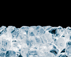 Frosted crushed heap of ice cubes in blue tone on black background.