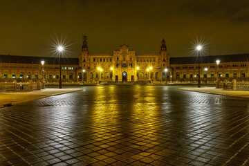 Plaza de España en Sevilla, Andalucía, foto nocturna con reflejo de luz en suelo y farolas con estrella de luz.