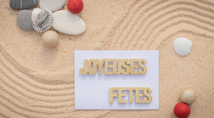 Fototapeta na wymiar Arrière-plan grains de sable de mer, sable fin de plage avec galets et coquillages. Message joyeuses fêtes. 