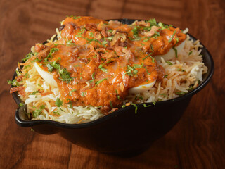 Traditional Egg Biryani - Basmati rice cooked with masala and spices and topped with sliced boiled eggs and anda curry, selective focus