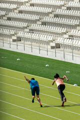 A pair of athletes rehearse the start on a green athletics track