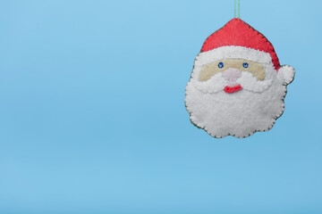 Ornament shaped Santa Claus in a red hat is on a blue background. The concept of a creative Christmas and new year. Copy space.