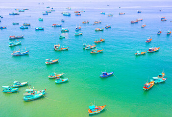 Fototapeta na wymiar Lot of colorful wooden Vietnamese traditional fisherman boats in the azure sea. The bay is crowded with boats. Top view
