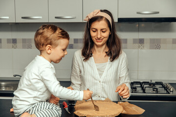 Mother and her boy making apple pie in their home kitchen.