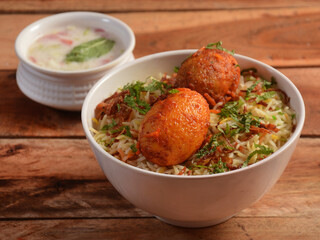 Egg Biryani - Basmati rice cooked with masala roasted eggs and spices and served with yogurt, selective focus