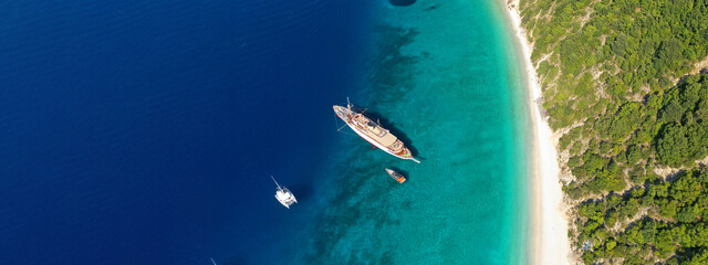 Aerial drone top down ultra wide photo of luxury yacht anchored in tropical exotic island turquoise...