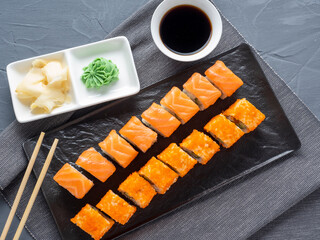 roll Philadelphia and California on a black plate. Top view, flat lay. ginger, wasabi and soy sauce...