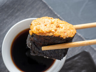 bamboo sticks hold a sharp gunkan. In the background is a bowl of soy sauce. Close up. traditional Japanese cuisine