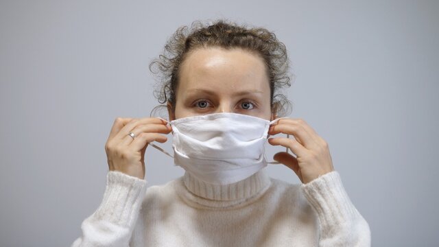 Preventive measures to save public healthcare system from collapse. Woman covers face with reusable mask before leaving home during second wave covid-19 pandemic