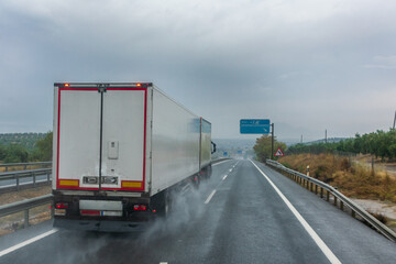 Truck with modular euro configuration driving on a highway on a rainy day.