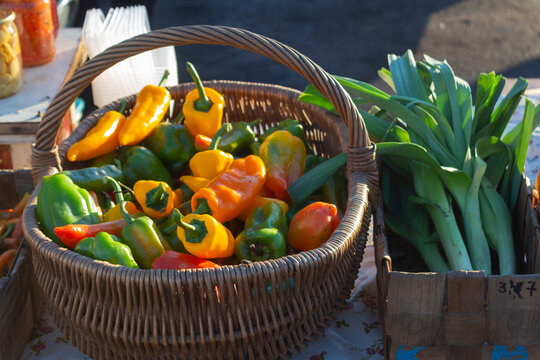 Ripe peppers in a basket and batun onions close-up on a rural market on an autumn sunny day
