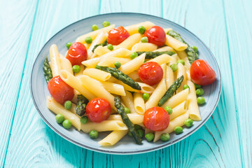 Penne pasta salad with asparagus , tomatoes and peas