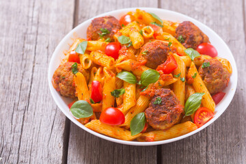 Italian penne pasta with meatballs and tomatoes