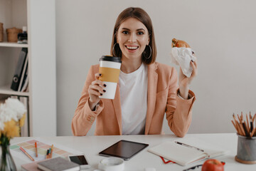 Joyful business woman looking at camera with smile while having lunch in bright office