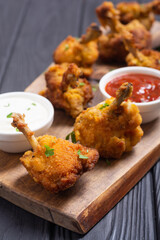 Chicken wings nuggets with sauces on wooden background .