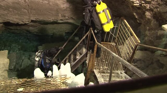 Speleodivers in diving suits descend into a cave lake, from which an underwater hole leads to the Orda underwater cave.