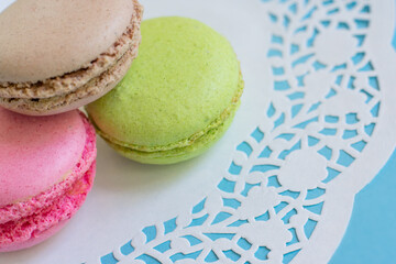 Colorful almond macarons on white napkin on blue background. French pastry sweet cookies with different flavors and colors