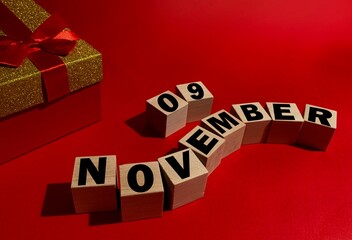 November 9 on wooden cubes ,red gift box on a red background.Autumn .Calendar for November.