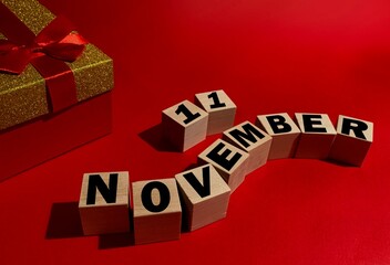 November 11 on wooden cubes ,red gift box on a red background.Autumn .Calendar for November.