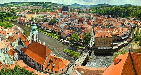 Panoramic view from the tower Hradek of Czech city Cesky Krumlov. European tile roof houses, a river and a bridge over it full of people in South Bohemian Region.