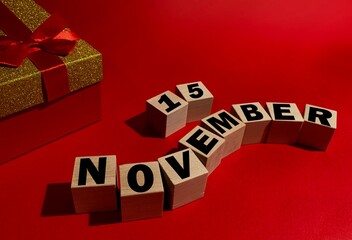 November 15 on wooden cubes ,red gift box on a red background.Autumn .Calendar for November.
