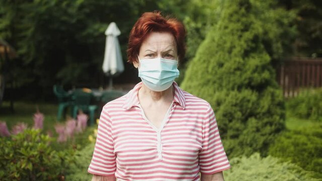 Old woman wearing a protective medical face mask during Covid 19 pandemic.