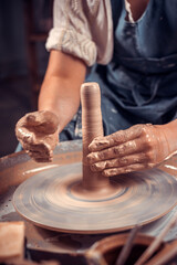 Potter's hands and potter's wheel. Close-up.
