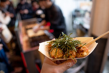 Naklejka premium Holding a boat of Teppanyaki Balls with seaweed on top, street food, osaka, japan, December 17, 2018