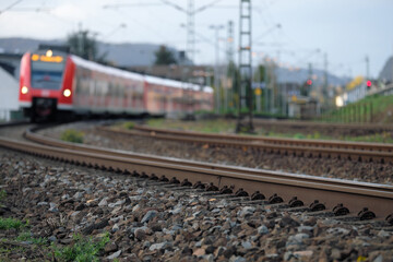Gleisbett mit Gleisschotter und Schienenstrang und Nahverkehrszug in einer Kurve auf der Rheinstrecke bei Leutesdorf am Mittelrhein in Rheinland-Pfalz- Stockfoto