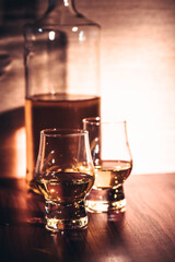 Selective focus glasses of whiskey on rustic wood background, Alcohol drink whiskey or bourbon with ice cubes on wood table together while at bar counter in the pub.