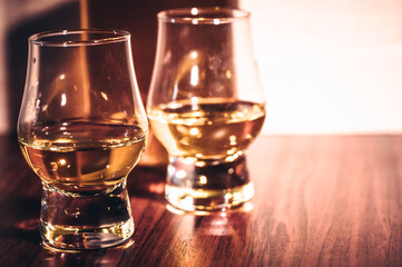 Selective focus glasses of whiskey on rustic wood background, Alcohol drink whiskey or bourbon with ice cubes on wood table together while at bar counter in the pub.