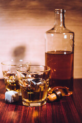 Selective focus glasses of whiskey on rustic wood background, Alcohol drink whiskey or bourbon with ice cubes on wood table together while at bar counter in the pub.