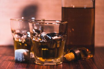 Selective focus glasses of whiskey on rustic wood background, Alcohol drink whiskey or bourbon with ice cubes on wood table together while at bar counter in the pub.