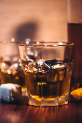 Selective focus glasses of whiskey on rustic wood background, Alcohol drink whiskey or bourbon with ice cubes on wood table together while at bar counter in the pub.
