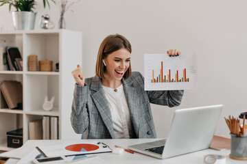Close-up shot of happy business woman in stylish outfit. Girl in high spirits demonstrates chart...