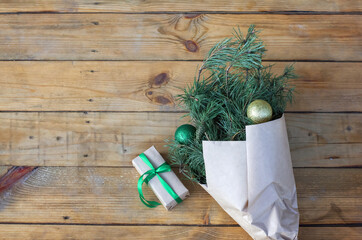 Winter rustic bouquet with fir branches. Branches of Christmas tree in the kraft paper on a wood background, zero waste. Christmas bouquet top view. Eco friendly packaging, gift.