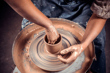 Artisan making pottery, sculptor from wet clay on wheel. Making ceramic dishes. Close-up.