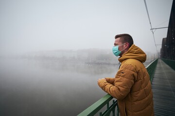 Lonely man wearing face mask against city in fog