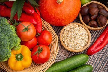Group vegetables and Fruits Apples, grapes, oranges, and bananas in the wooden basket with carrots, tomatoes, guava, chili, eggplant, and salad on the table.Healthy food concept