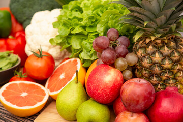Group vegetables and Fruits Apples, grapes, oranges, and bananas in the wooden basket with carrots, tomatoes, guava, chili, eggplant, and salad on the table.Healthy food concept