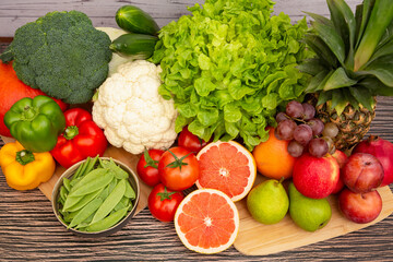 Group vegetables and Fruits Apples, grapes, oranges, and bananas in the wooden basket with carrots, tomatoes, guava, chili, eggplant, and salad on the table.Healthy food concept